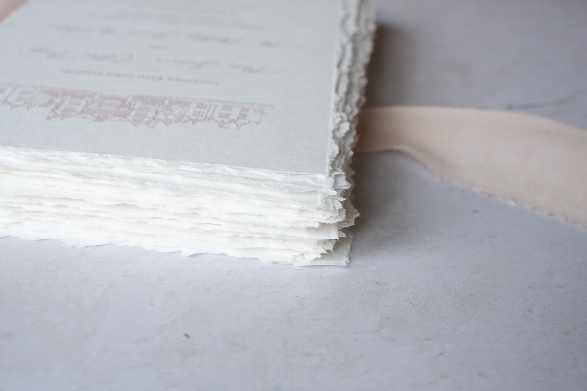 Elegant hand torn recycled paper on heirloom wedding invitation