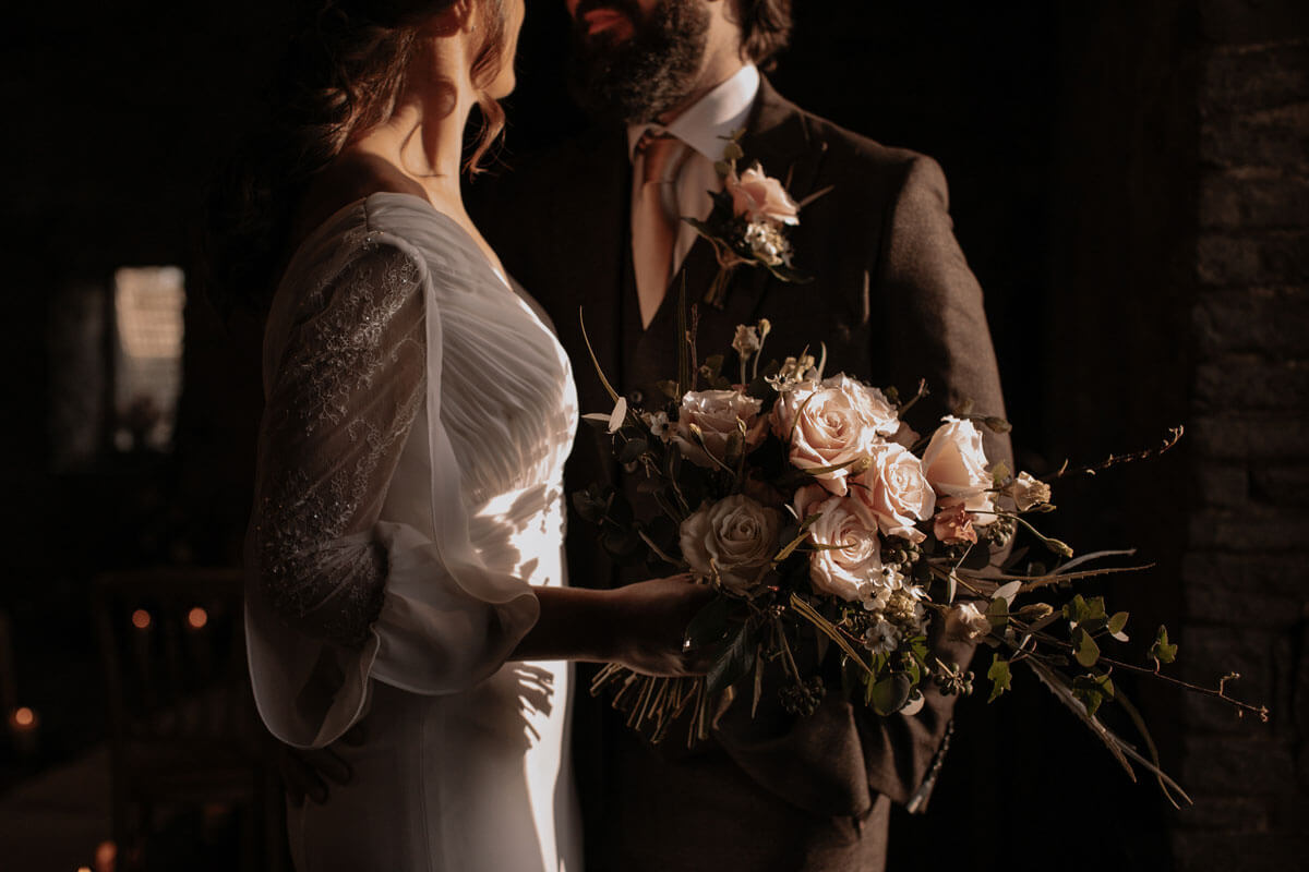 Bride and groom for cosy winter wedding. Bride in long sleeved wedding dress and brown tweed suit.