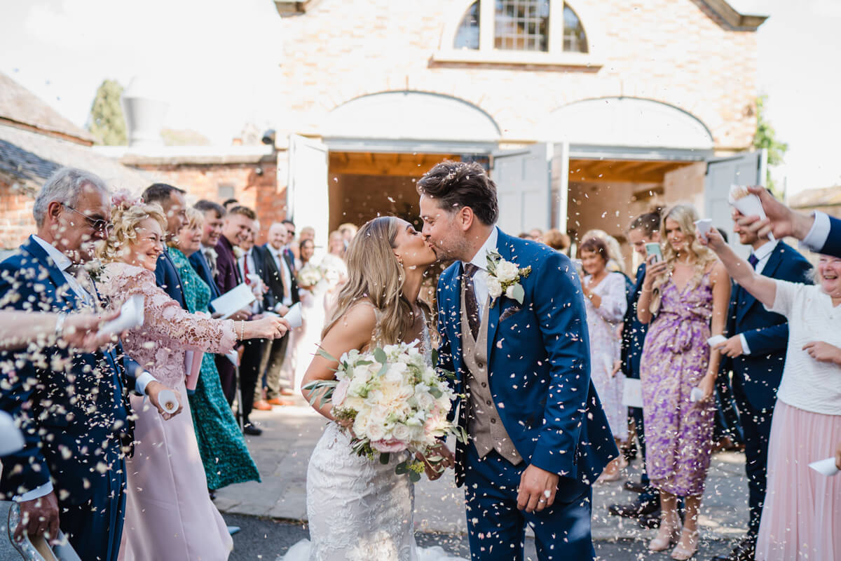 Bride and Groom kissing under confetti at Dorfold Hall Wedding
