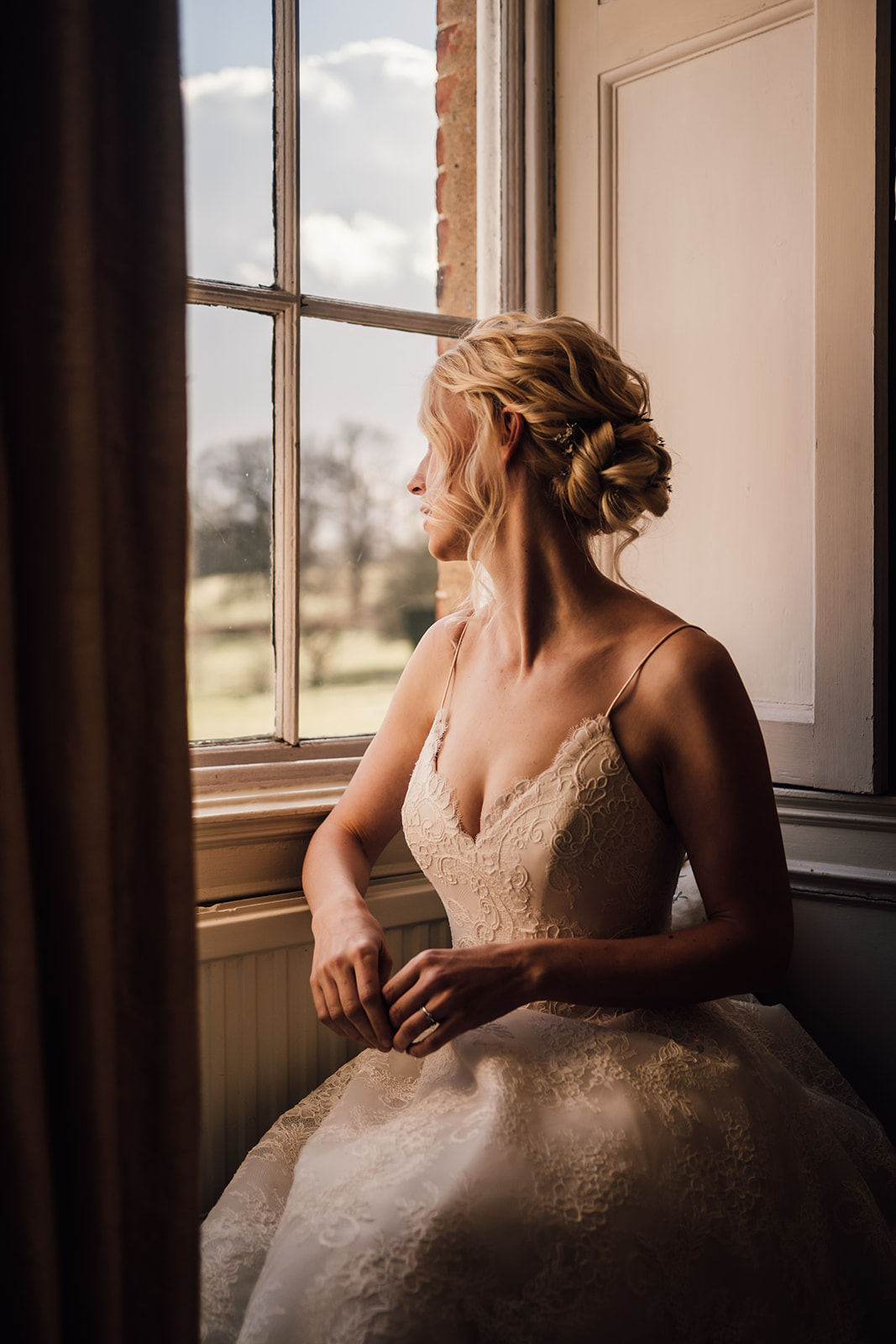Bride sat looking out window in long gallery at Norwood Park